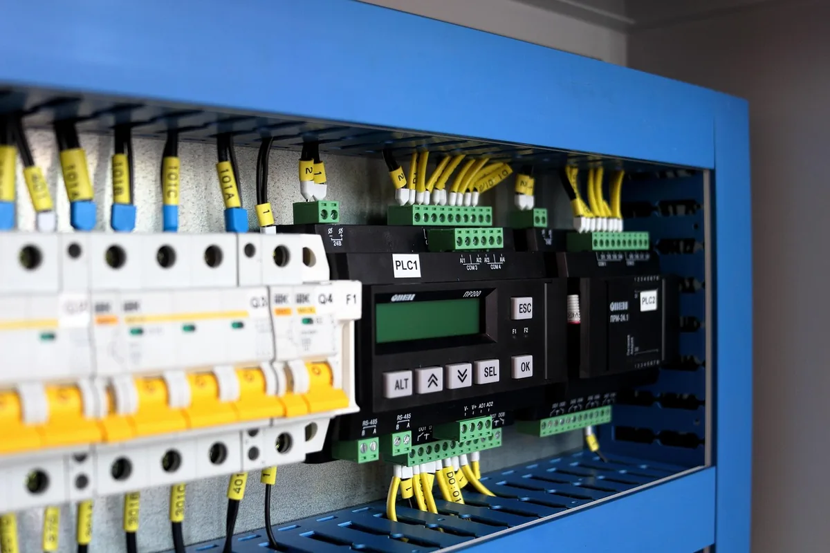 Armoire électrique bleue ouverte avec disjoncteurs et module automate
