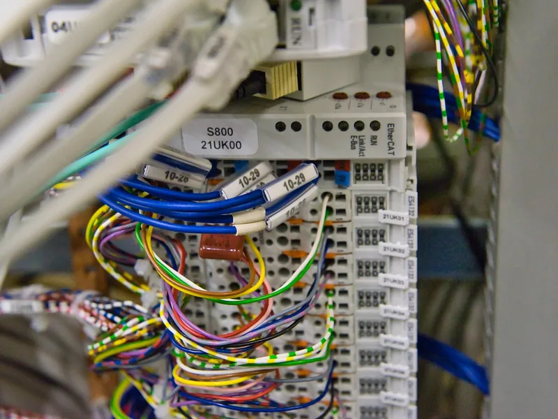 Gros plan sur des borniers repérés et des fils colorés dans une armoire électrique