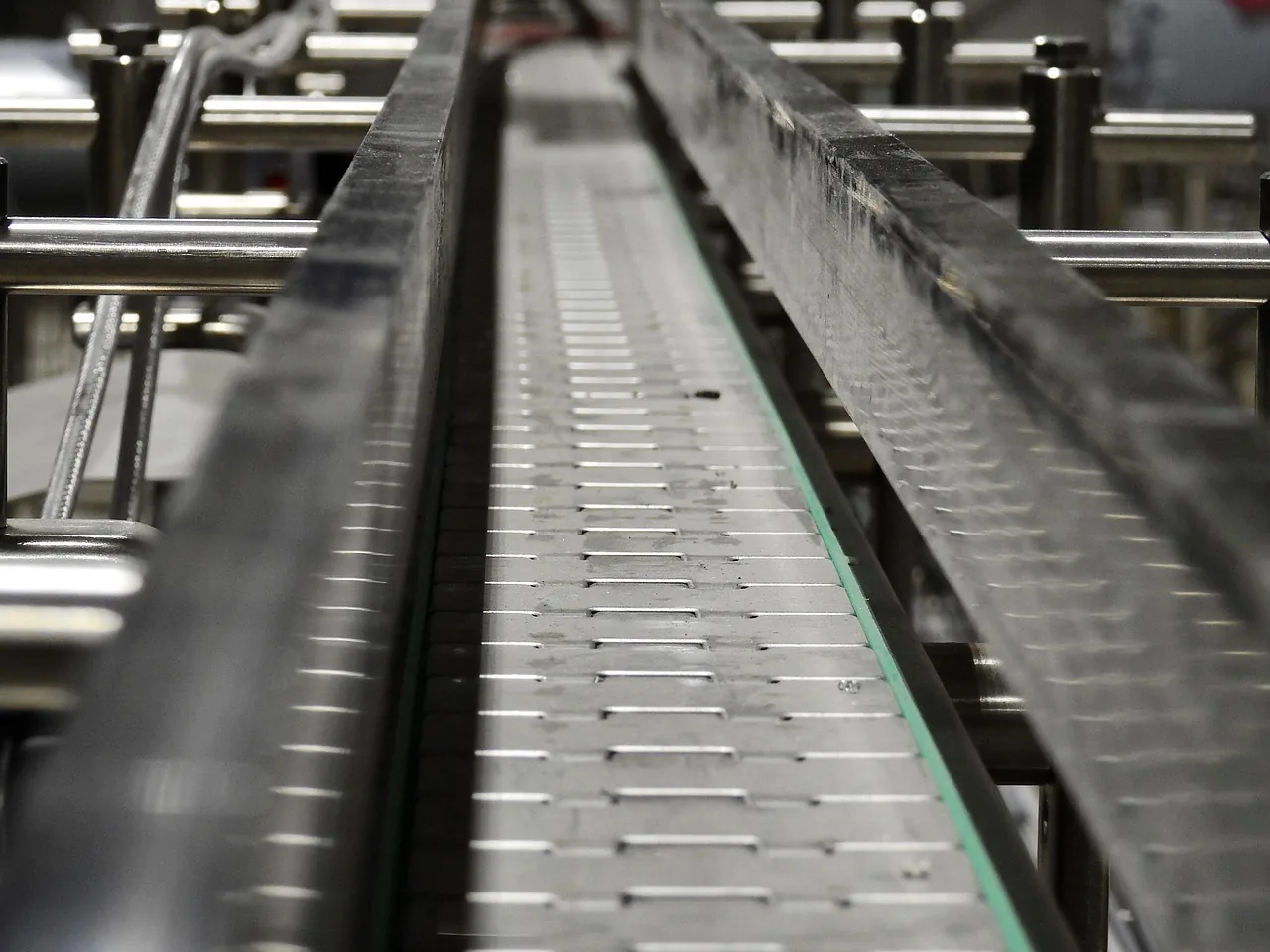 Convoyeur à chaîne en inox vu en perspective sur une ligne de production