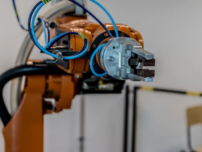 Pince d'un robot industriel orange avec câbles et flexibles pneumatiques