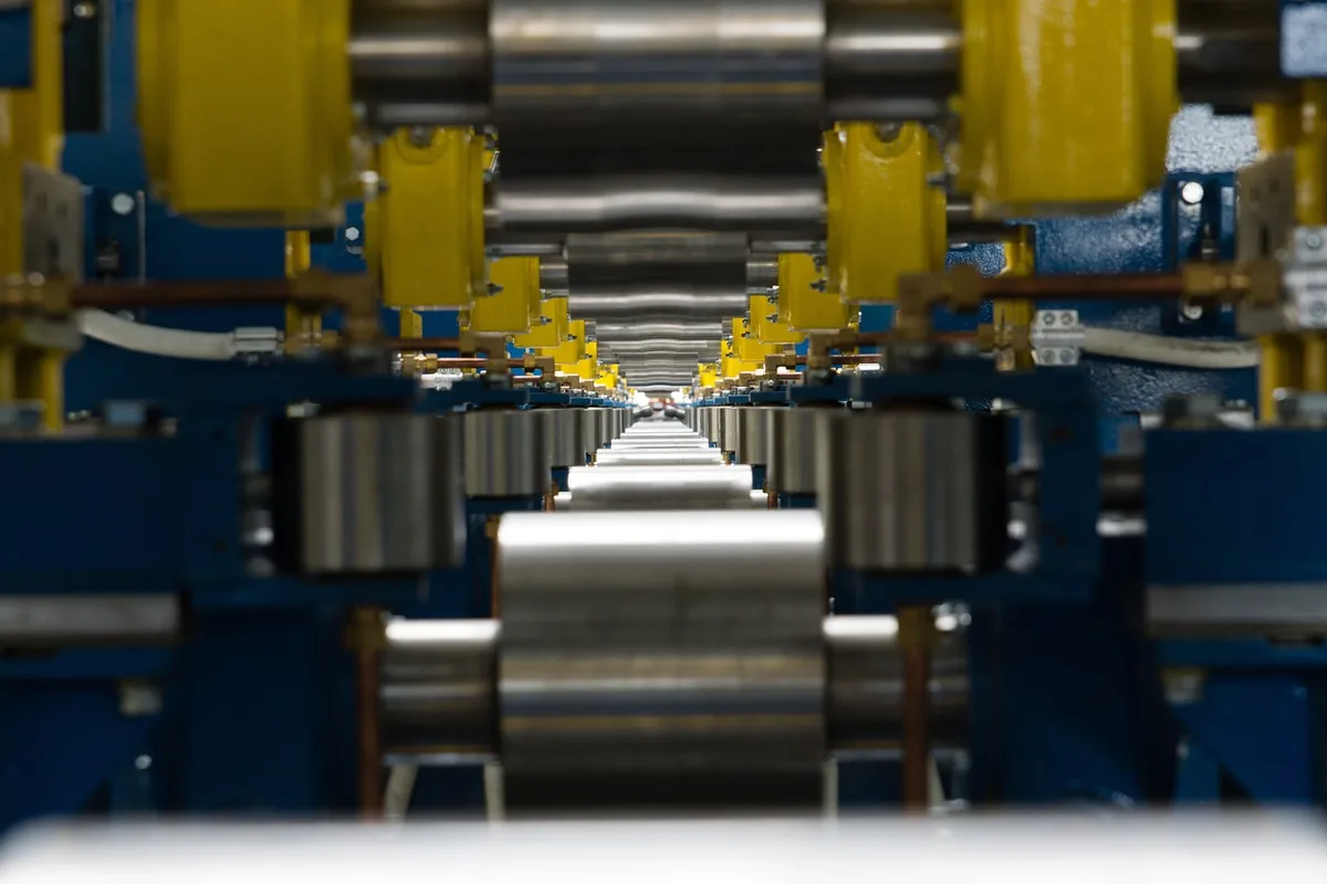 Rouleaux d'acier alignés sur une ligne de production métallurgique, vue en perspective